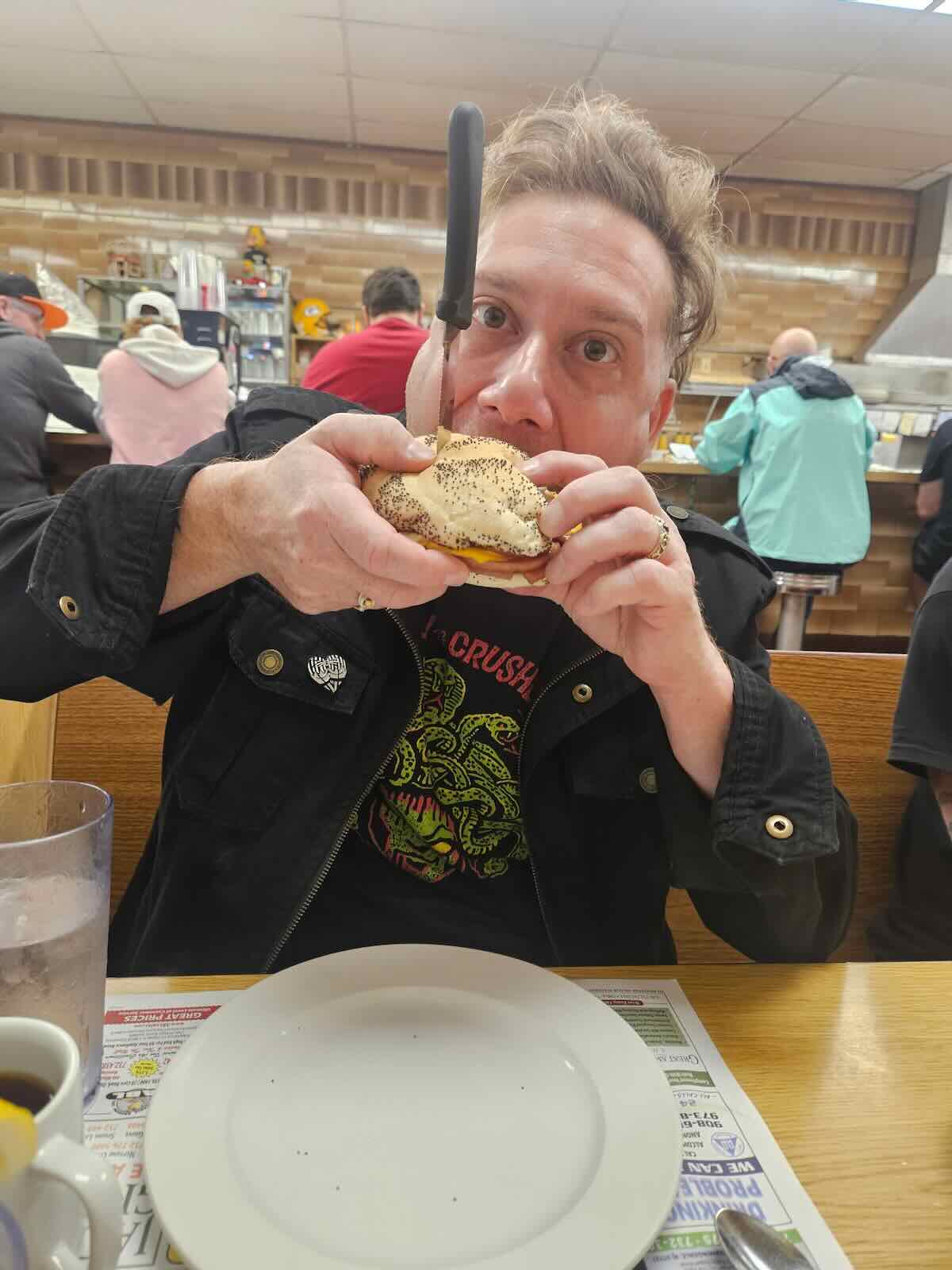A person eating a sandwich at Frank's Deli